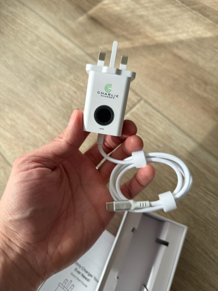 Charlie Charger final production unit — 30W USB-C wall charger with fingerprint sensor, held in hand with retail packaging