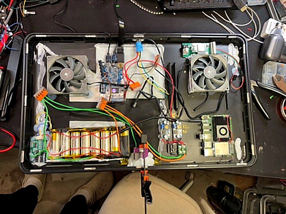 Top-down view of Genboard internals — dual cooling fans, Radxa SBC, LiPo battery pack, power management, LTE module